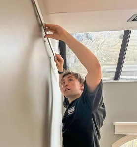 Installer installing a picture hanging system